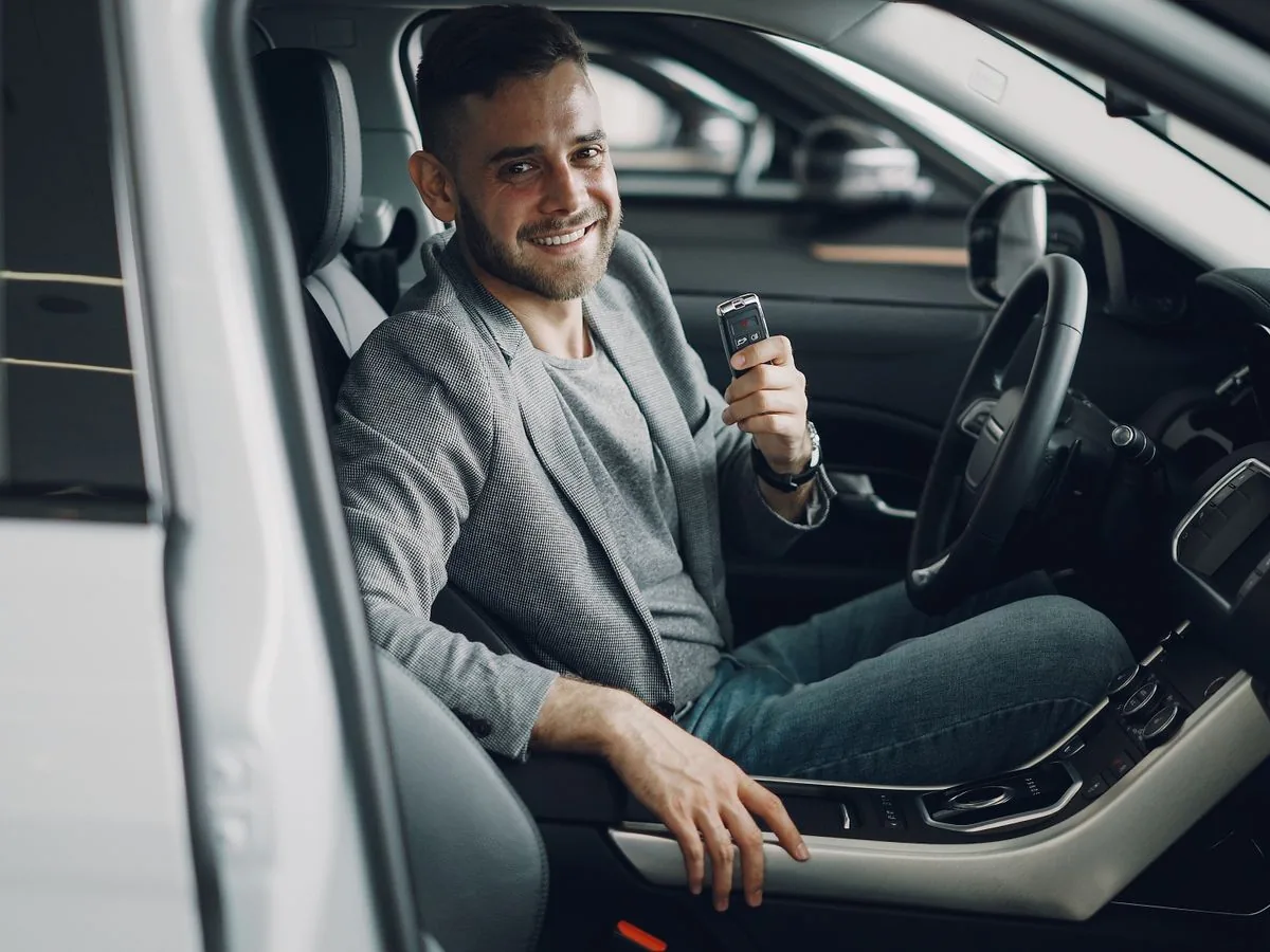 Nouveau conducteur souriant avec les clés de son véhicule après l'obtention du permis