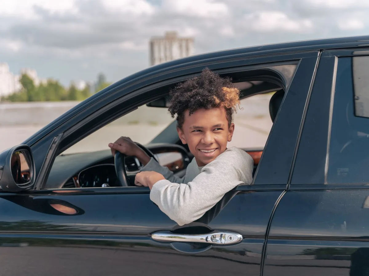 Jeune conducteur souriant au volant grâce au permis à 1€ par jour